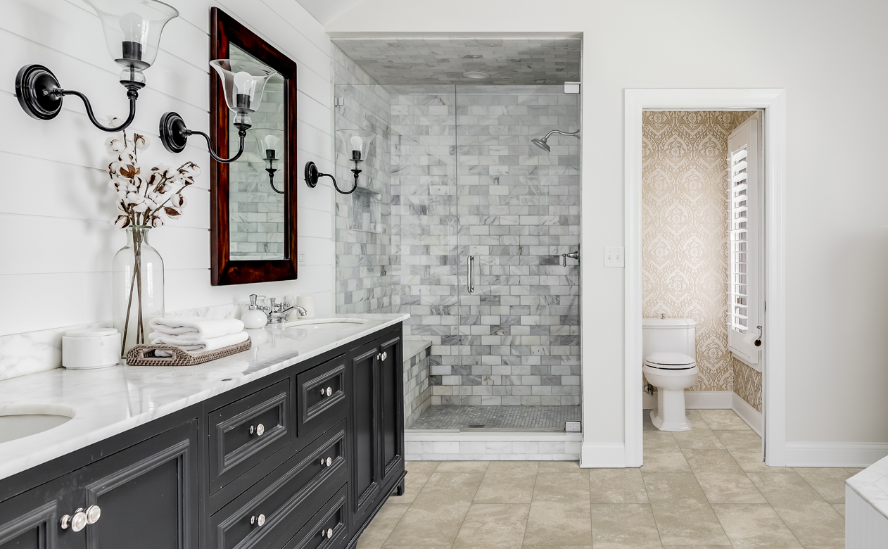 Light brown tile flooring in bathroom with marble subway tile shower surround and dark brown cabintry